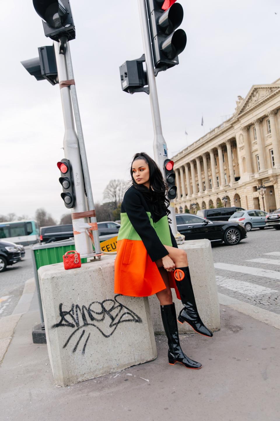 Sai De Silva in Paris wearing Christian Dior’s coat and boots with rubberized detailing. - Credit: Allie Provost