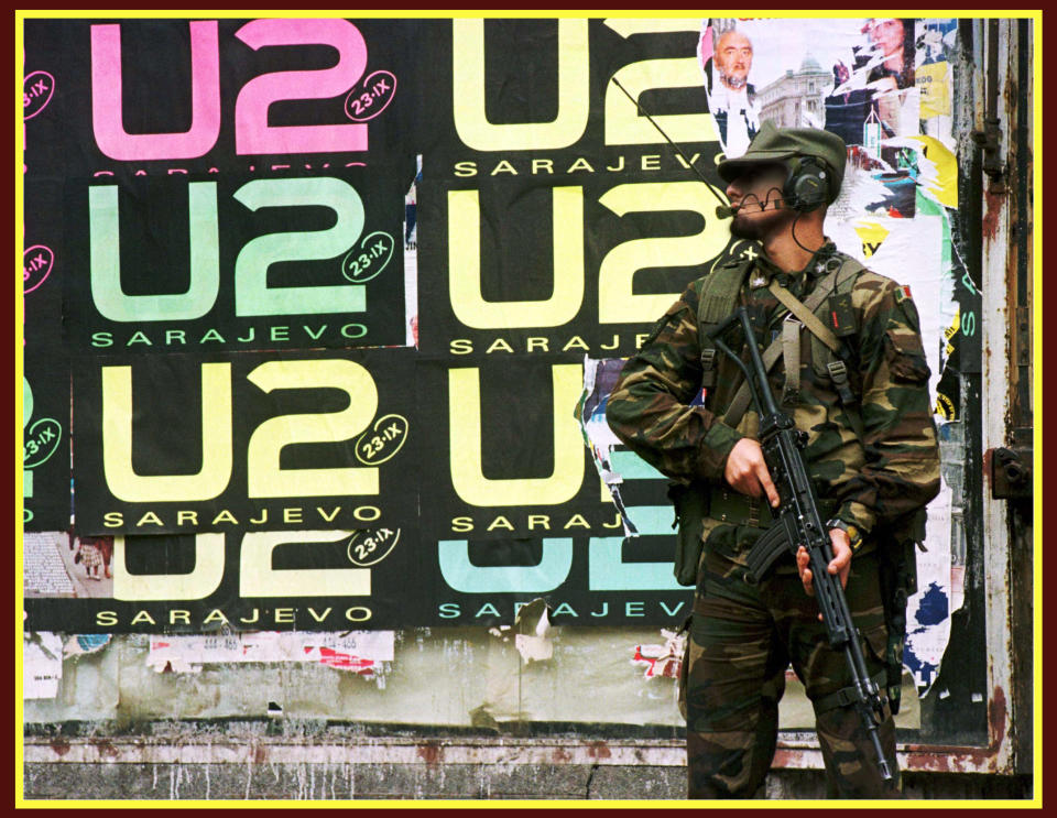An Italian peacekeeper holds his rifle as he stands in front of wall covered with U2 posters in center Sarajevo September 21, 1997. 