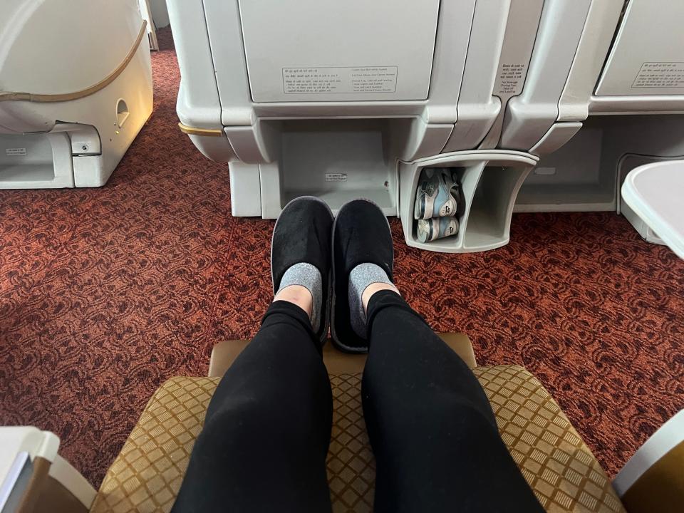 The author's legroom, wearing black slippers and black leggings.