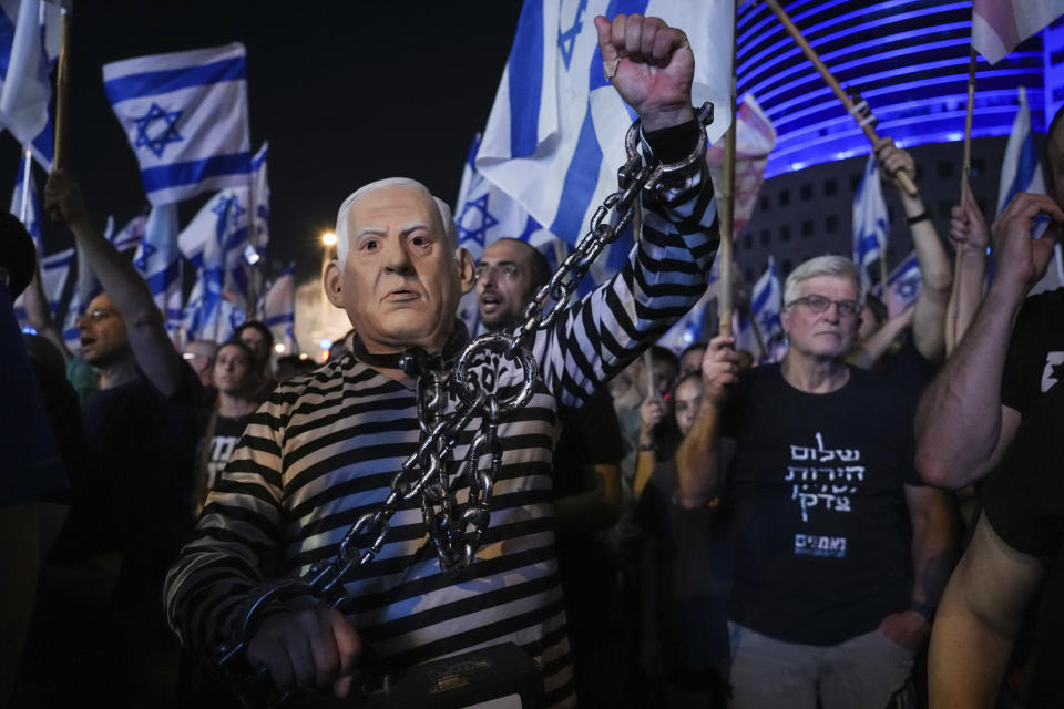 A demonstrator wearing a rubber mask depicting Israeli Prime Minister Benjamin Netanyahu during a protest against plans by his government to overhaul the judicial system, in Tel Aviv, Israel, Saturday, June 10, 2023. (AP Photo/Tsafrir Abayov)