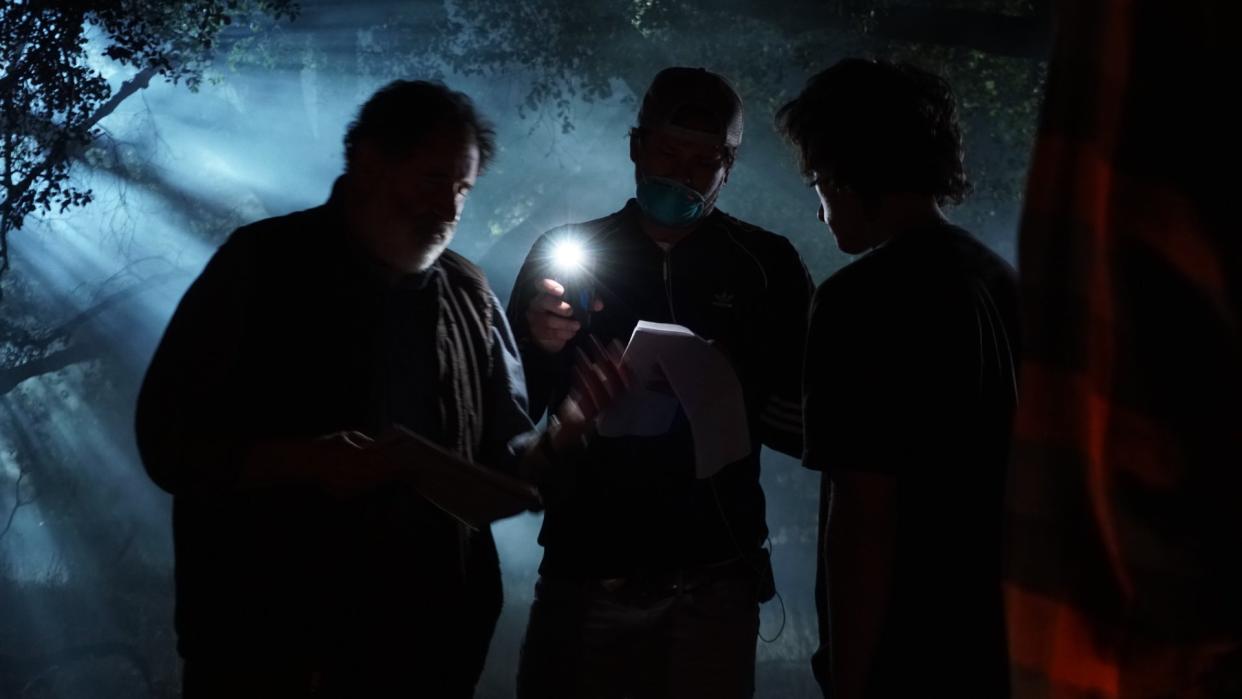  Three people stand in the forest at night. 