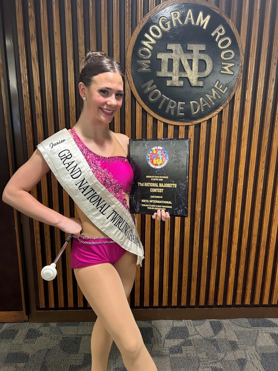 Micah Beaudoin, an Arlington High School student, poses with her plaque after being named grand champion of a national twirling competition in Indiana last July.