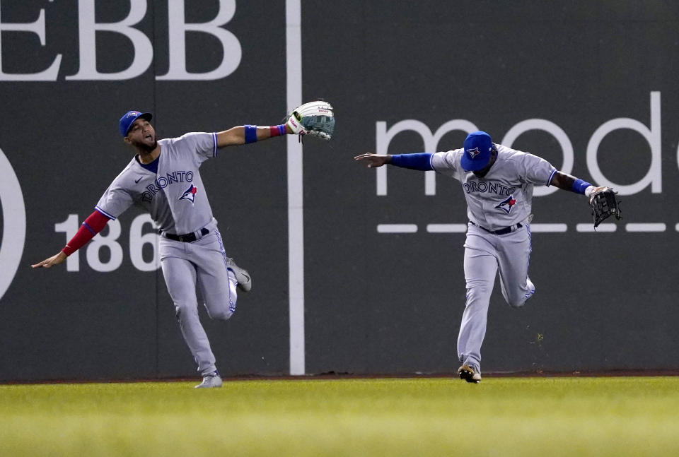 Toronto Blue Jays left fielder Lourdes Gurriel Jr., left, and center fielder Jackie Bradley Jr. celebrate after defeating the Boston Red Sox during the tenth inning of a baseball game at Fenway Park, Wednesday, Aug. 24, 2022, in Boston. (AP Photo/Mary Schwalm)