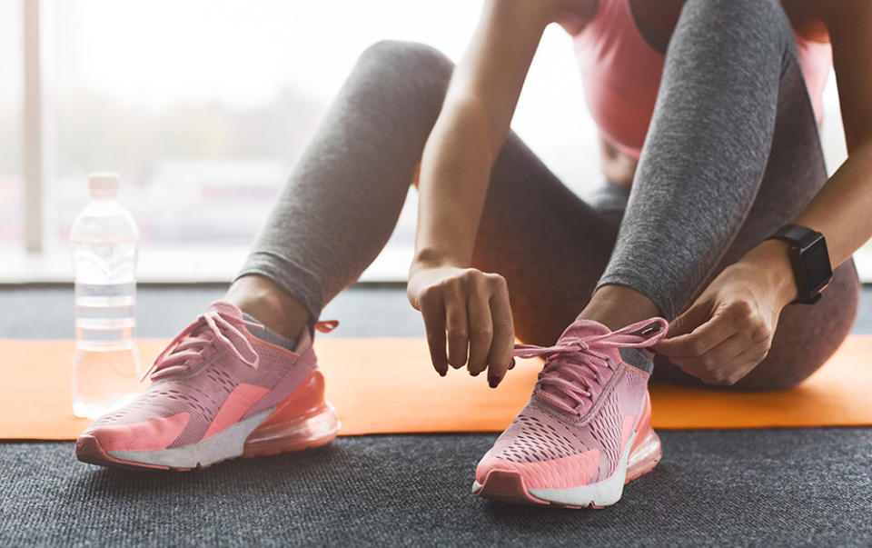 Woman in workout leggings tying the laces on her runners