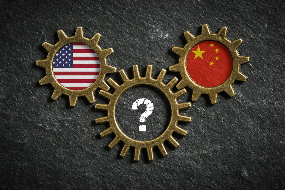 Three interlocking cogs displaying the U.S. flag, China flag, and a question mark.