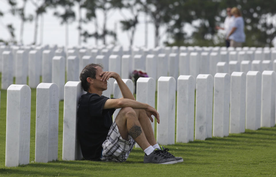 Jeff Lee of Lantana, Florida, leans against the gravestone of his father, Frank Lee, during a Memorial Day ceremony at the South Florida National Cemetery in Lake Worth, Florida, on May 27, 2013.