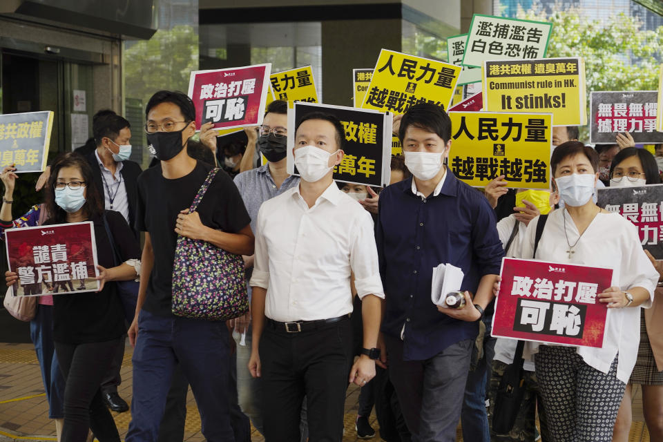 Pro-democracy lawmakers, from second left to right, Eddie Chu, Raymond Chan, and Ted Hui walk with supporters at a local court in Hong Kong, Thursday, Nov. 19, 2020. Three former pro-democracy lawmakers appeared in court Thursday, one day after they were arrested for disrupting the legislature during debate on a national anthem bill earlier this year. (AP Photo/Vincent Yu)