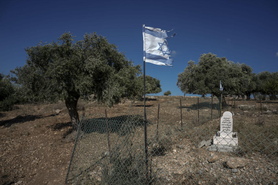 A partially torn Israeli flag is blown by the wind in a cemetery for Arab Bedouins who fell in the service of the state of Israel, on a hillside that might soon be forbidden to Bedouins community that has grazed goats on it for generations near Zubaydat, in the Galilee region, Israel, Tuesday, Aug. 23, 2022. Plans to turn the 2,500-acre area into a wildlife corridor have sparked rare protest from Bedouin in the northern Galilee region. (AP Photo/Ariel Schalit)