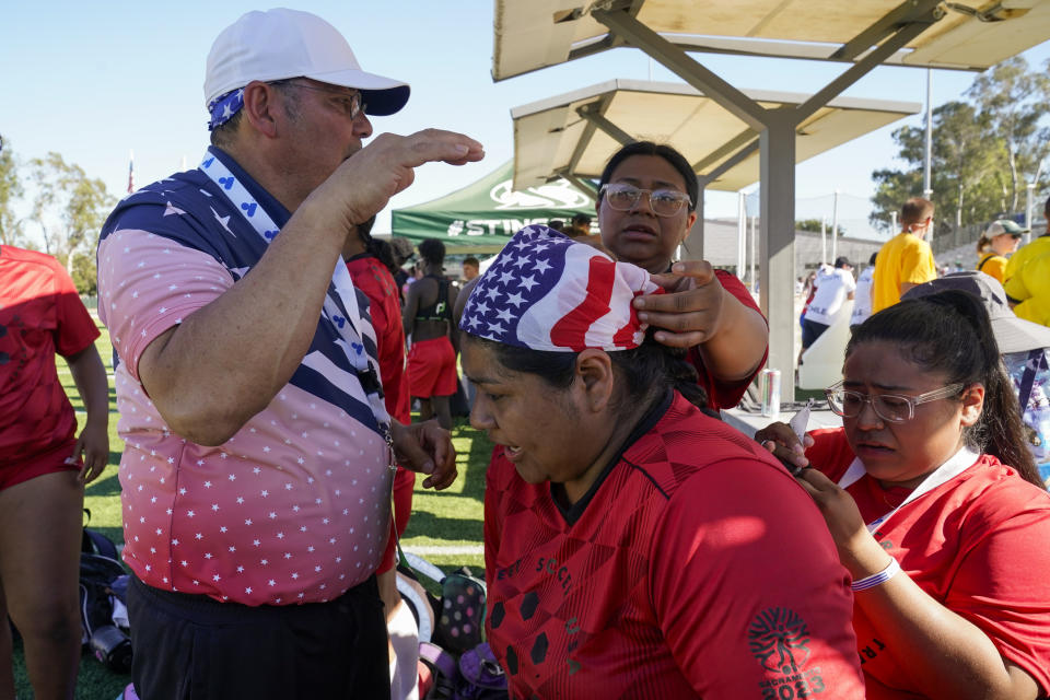 Francisca Pass, center, is helped by her teammates to get her hair ready for a match at the Homeless World Cup, Tuesday, July 11, 2023, in Sacramento, Calif. (AP Photo/Godofredo A. Vásquez)