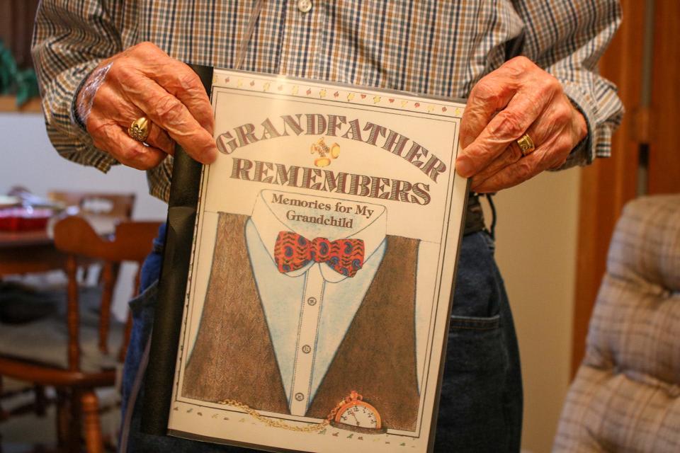 Marlin Ames holds a book he wrote for his grandchildren titled "Grandfather Remembers: Memories for My Grandchild." Ames said he created it since he never got to know his grandparents.