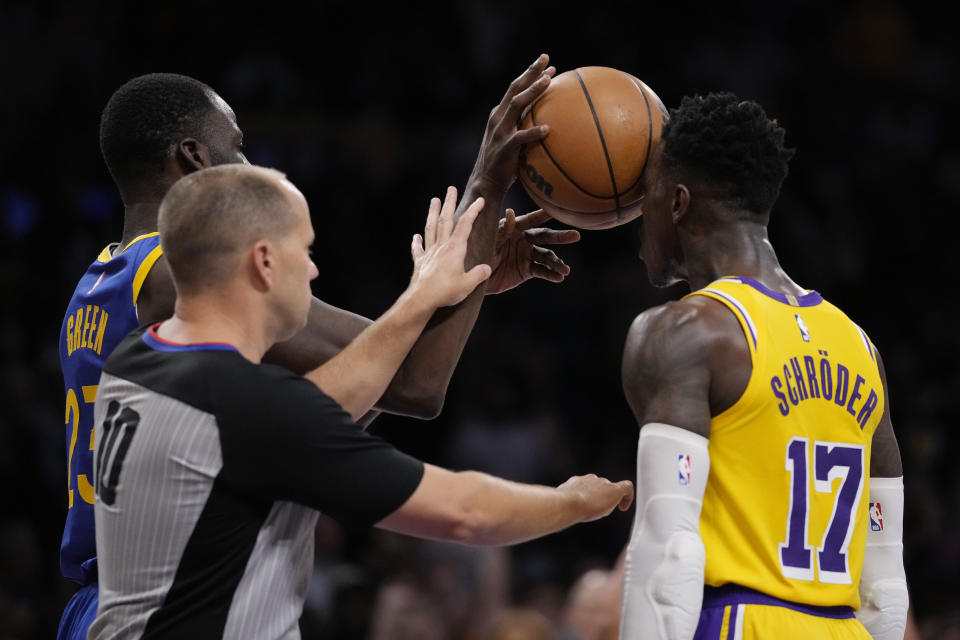 Golden State Warriors forward Draymond Green, left, shoves the ball in the face of Los Angeles Lakers guard Dennis Schroder (17) during the second half in Game 6 of an NBA basketball Western Conference semifinal series Friday, May 12, 2023, in Los Angeles. (AP Photo/Ashley Landis)