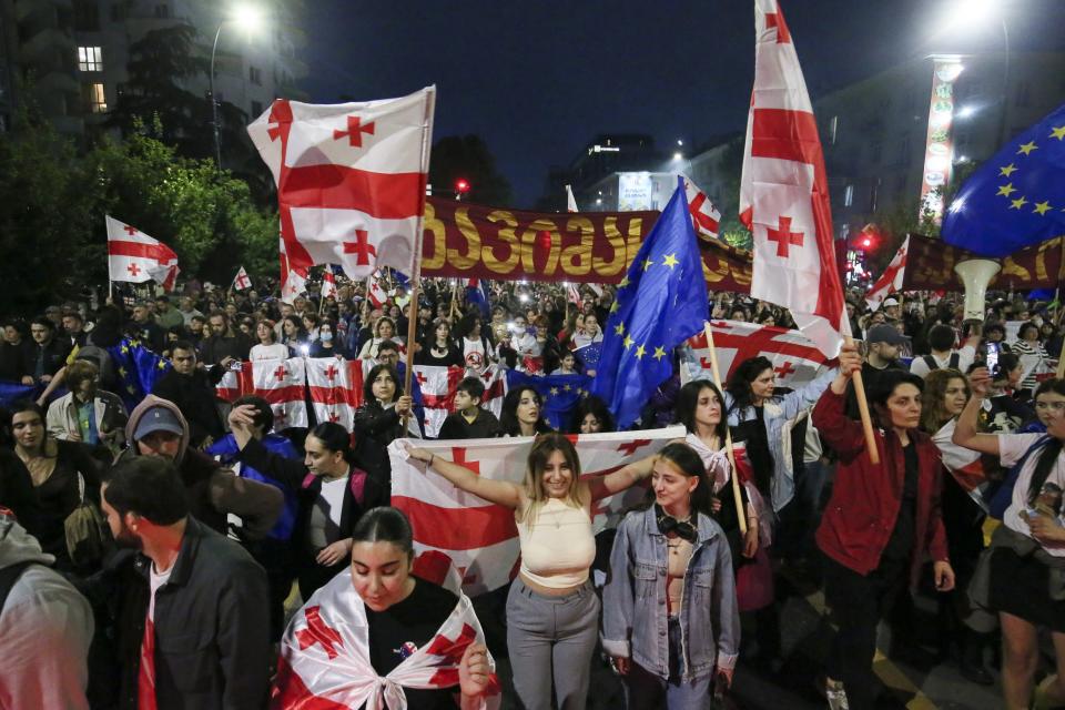 Demonstrators with Georgian national and EU flags rally during an opposition protest against a foreign influence bill and celebrating of the Independence Day in the center of in Tbilisi, Georgia, Sunday, May 26, 2024. The opposition has denounced the bill as "the Russian law," because Moscow uses similar legislation to crack down on independent news media, nonprofits and activists critical of the Kremlin. (AP Photo/Zurab Tsertsvadze)