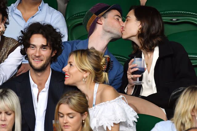 James Veysey/Shutterstock Alexa Chung and Tom Sturridge kiss while Sienna Miller and Oli Green talk at the 2022 Wimbledon Tennis Championships.