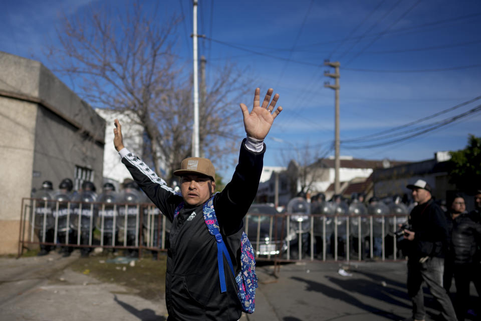 A demonstrator raises his arms as others throw missiles at police during a protest against the death of 11-year-old girl Morena Dominguez, who died from her injuries after criminals tried to rob her, outside a police station on the outskirts of Buenos Aires, Argentina, Wednesday, Aug. 9, 2023. (AP Photo/Natacha Pisarenko)