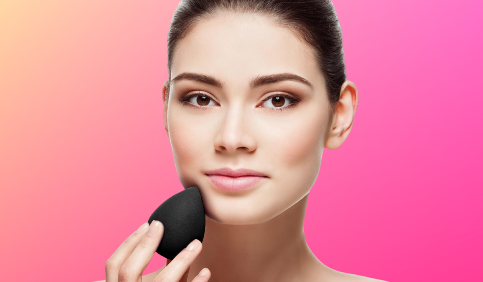 Woman touching Aesthetica blender beauty sponge to face