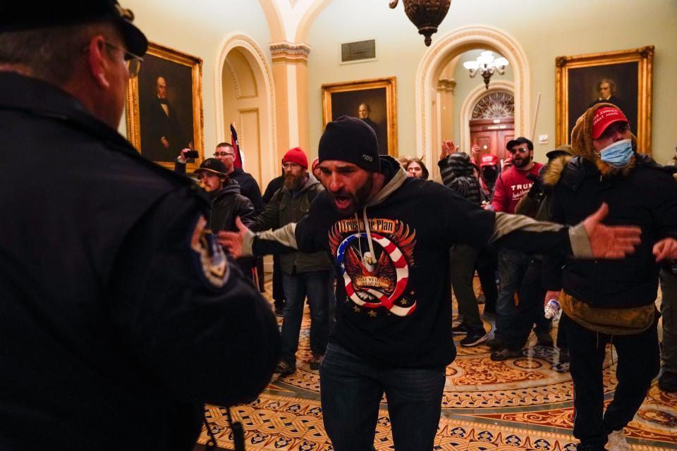 Protesters gesture to U.S. Capitol Police in the hallway outside of the Senate chamber at the Capitol in Washington, Wednesday, Jan. 6, 2021, near the Ohio Clock. At center is Doug Jensen of Des Moines, Iowa who was later arrested and charged, the Des Moines Register reported.