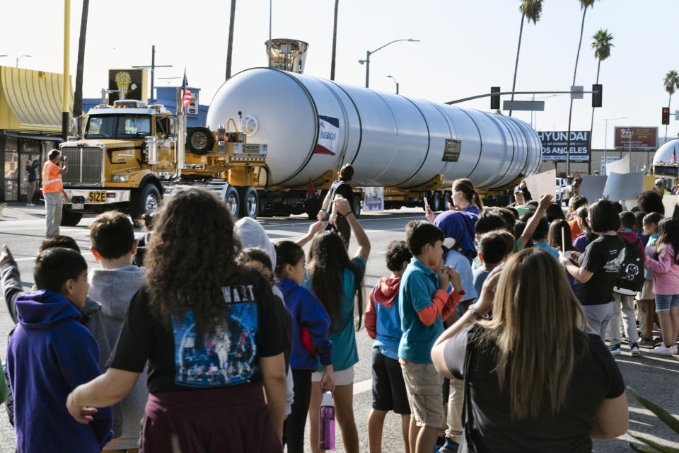 Students from the Alexander Science Center School cheer as two rocket motors are moved slowly down Figueroa Street in Los Angeles, Wednesday Oct. 11, 2023. The giant rocket motors, required to display the retired NASA space shuttle Endeavour as if it’s about to blast off, were trucked over two days from Mojave Air and Space Port to LA’s Exposition Park. (AP Photo/Richard Vogel)