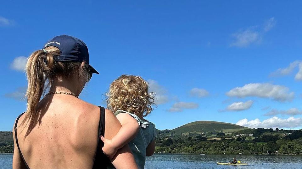 Helen Skelton posing in swimsuit on lake while holding daughter Elsie