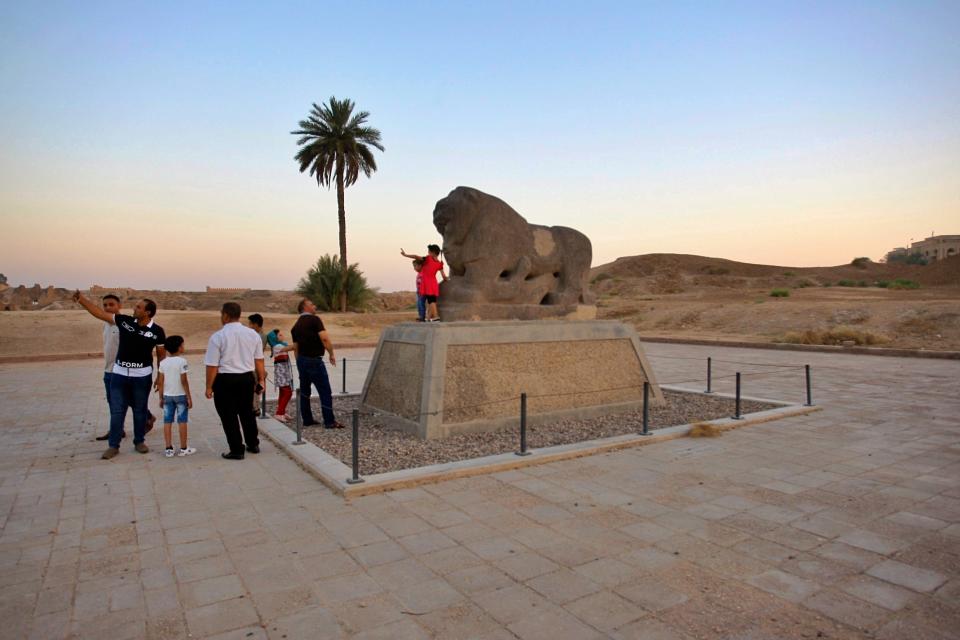 People stand near the Lion of Babylon at the archaeological site of Babylon, Iraq, Friday, July 5, 2019. Iraq on Friday celebrated the UNESCO World Heritage Committee's decision to name the historic city of Babylon a World Heritage Site in a vote held in Azerbaijan's capital, years after Baghdad began campaigning for the site to be added to the list. (AP Photo/Anmar Khalil)