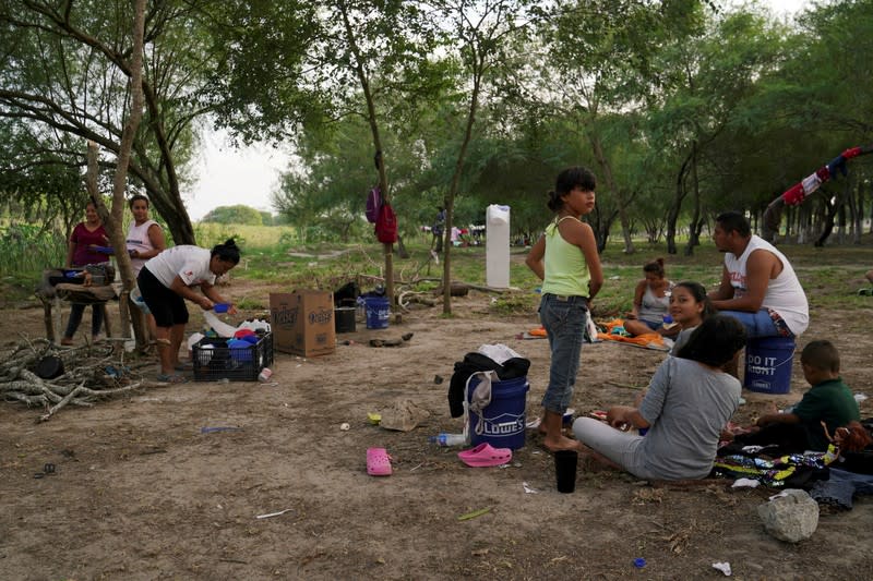 FILE PHOTO: Asylum seekers eat while others cook food in a mud stove in an encampment where they live after being sent back to Mexico under the Migrant Protection Protocols (MPP) in Matamoros