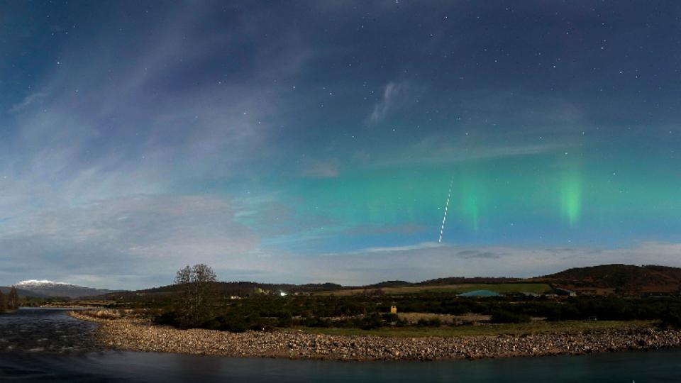 Green auroras with a meteor streaking through the sky