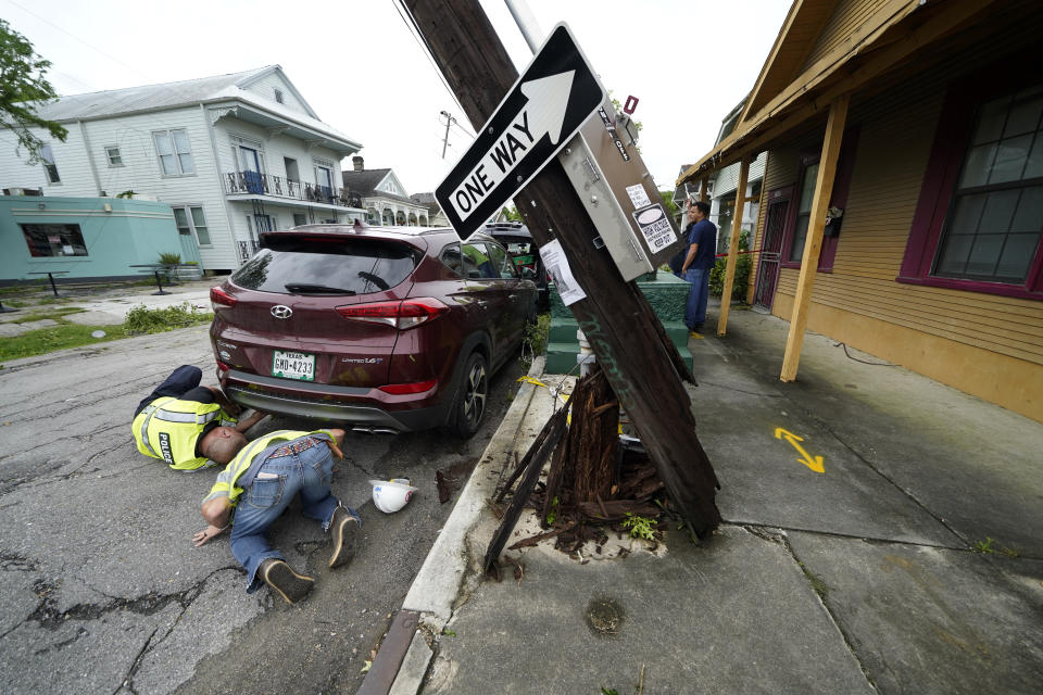 Responders inspect underneath a car next to a damaged utility pole from a possible tornado after heavy storms moved through the area Tuesday night, in the Uptown section of New Orleans, Wednesday, May 12, 2021. (AP Photo/Gerald Herbert)