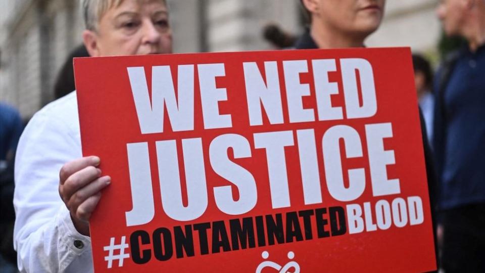 Demonstrators hold placards with message related to the NHS infected blood scandal Prime Minister Rishi Sunak gives evidence to the Infected Blood Inquiry, in London, on 26 July, 2023