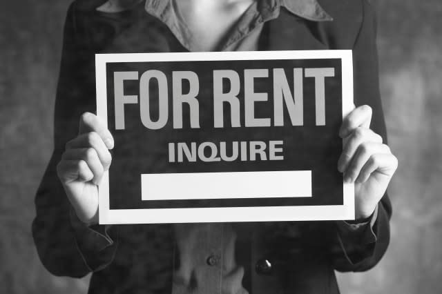 Woman holding up a For Rent sign