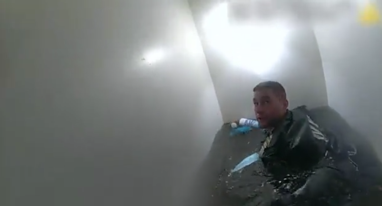 An NYPD officer wading through the flooded basement apartment in Queens where three people were later found dead (Screengrab/NYPD)