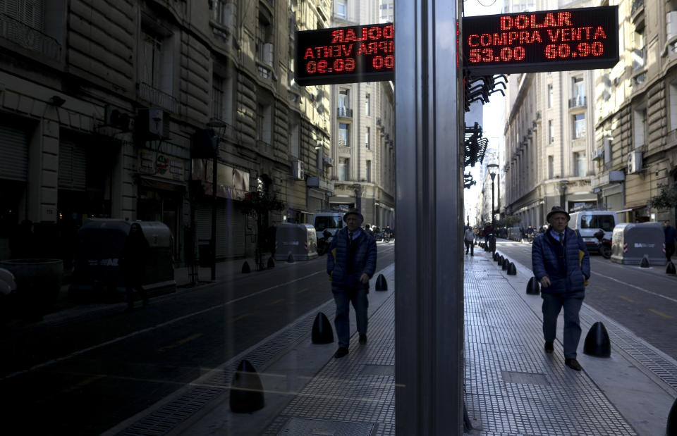 A man walk past a currency exchange board in Buenos Aires, Argentina, Wednesday, Aug. 14, 2019. President Mauricio Macri announced economic relief for poor and working-class Argentines that include an increased minimum wage, reduced payroll taxes, a bonus for informal workers and a freeze in gasoline prices. (AP Photo/Natacha Pisarenko)
