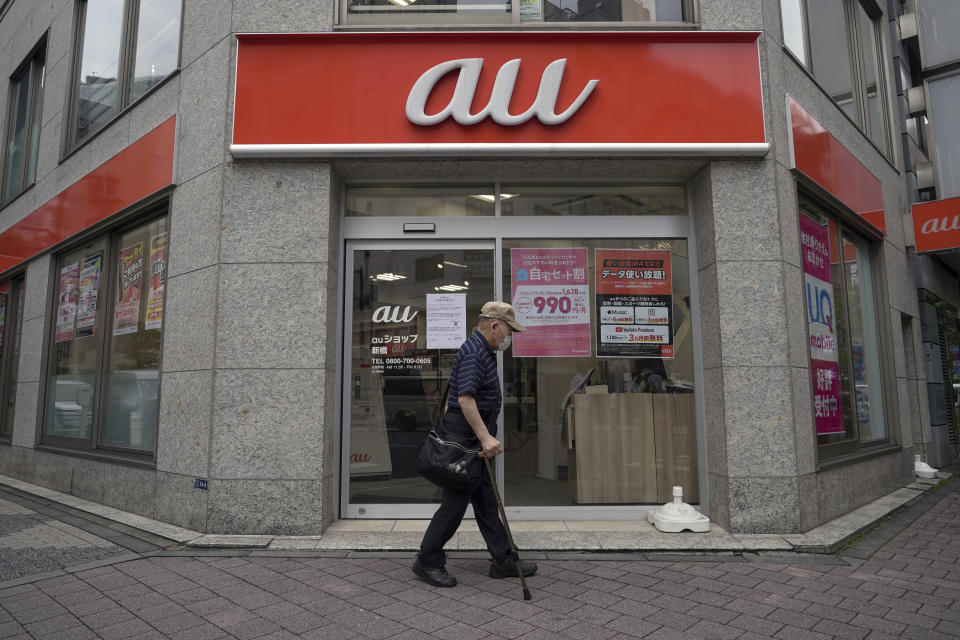 A person walks past an "au" mobile brand operator shop, of KDDI Corp., Monday, July 4, 2022, in Tokyo. Many users of Japan’s No. 2 mobile carrier KDDI Corp. were still having trouble making calls Monday after a massive outage throughout the weekend that affected nearly 40 million people, disrupting deliveries, weather reports and other services across the country. (AP Photo/Eugene Hoshiko)