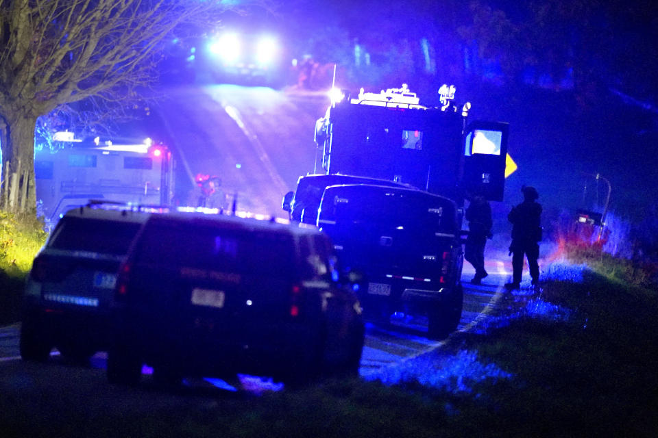 Law enforcement officers, right, stand near armored and tactical vehicles, center, near a property on Meadow Road, in Bowdoin, Maine, following a mass shooting, Thursday, Oct. 26, 2023. An independent commission investigating the deadliest shooting in Maine, that left 18 dead, released their interim report on Friday, March 15, 2024. (AP Photo/Steven Senne, File)