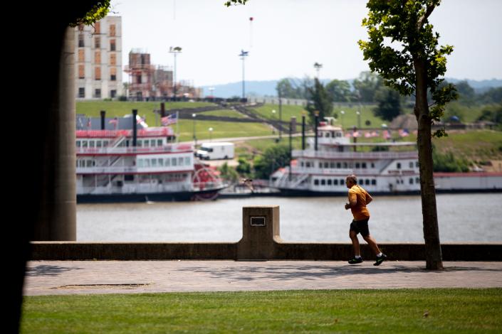 A pedestrian runs at Sawyer Point Park and Yeatman's Cove in Cincinnati on Wednesday, June 22, 2022. The heat index Wednesday was valued at 100-104 degrees.
