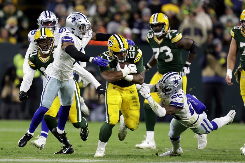 Green Bay Packers running back AJ Dillon (28) runs the ball as Dallas Cowboys cornerback Kelvin Joseph, left, and DaRon Bland (26) make the stop during the second half of an NFL football game Sunday, Nov. 13, 2022, in Green Bay, Wis. (AP Photo/Matt Ludtke)