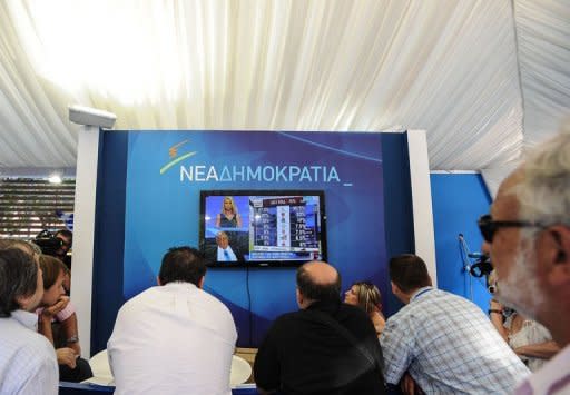 New Democracy (ND) party supporters watch the exit polls at the party's main election campaign kiosk in Athens. Greece's conservative New Democracy party and the radical left Syriza party were running neck-and-neck according to exit polls released immediately after ballots closed a historic election