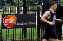 A jogger runs past a signage for pharmaceutical giant GlaxoSmithKline (GSK) in London April 22, 2014. Shares in European drugmakers received a shot in the arm on Tuesday amid a flurry of activity, with Novartis striking a multi-billion dollar deal with GSK and reports U.S. giant Pfizer had approached Britain's AstraZeneca over a deal. REUTERS/Luke MacGregor (BRITAIN - Tags: HEALTH BUSINESS) - RTR3M7LO