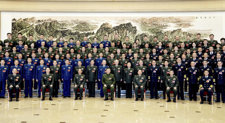 In this photo released by Xinhua News Agency, Chinese President Xi Jinping, bottom center, also general secretary of the Communist Party of China Central Committee and chairman of the Central Military Commission, poses for a group photo with deputies from the delegation of the People's Liberation Army (PLA) and the People's Armed Police Force before attending a plenary meeting of the delegation during the first session of the 14th National People's Congress (NPC) in Beijing, on Wednesday, March 8, 2023. Xi has called for "more quickly elevating the armed forces to world-class standards," in a speech coming days after he warned the country was threatened by a U.S.-led campaign of "containment, encirclement and suppression of China." (Li Gang/Xinhua via AP)