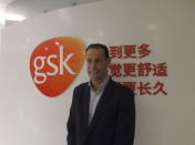 Herve Gisserot, general manager for GSK China, poses for a photograph in front of a company logo during an interview with Reuters at an office in Shanghai, China, November 25, 2015. REUTERS/Ben Hirschler