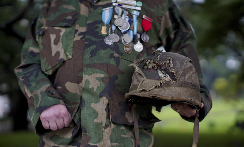 Argentine war veteran Jorge Altieri poses for a portrait with the blood-stained helmet, recently returned to him, that saved his life in 1982 during the Falklands war, in Buenos Aires, Argentina, Tuesday, March 12, 2019. "I have it next to me now and I use it like a teddy bear," Altieri said. "I look at it and I get teary-eyed from all the memories." (AP Photo/Natacha Pisarenko)