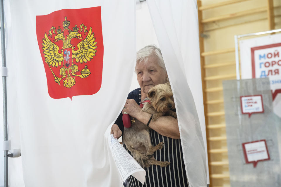 An elderly woman with her dog exits a polling booth before casting at a polling station during a city council election in Moscow, Russia, Sunday, Sept. 8, 2019. Residents of Russia's capital are voting in a city council election that is shadowed by a wave of protests that saw the biggest demonstrator turnout in seven years and a notably violent police response. (AP Photo/Pavel Golovkin)