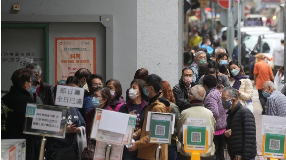 People wearing face masks queue outside a community vaccination centre to receive a dose of Sinovac Biotech