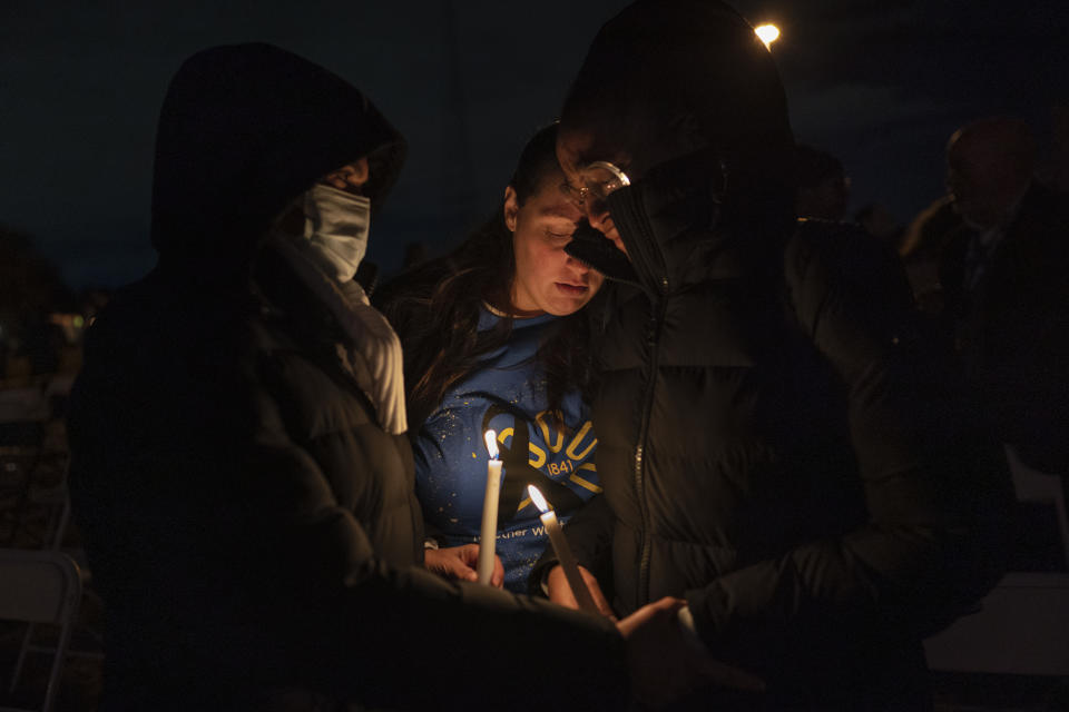 People comfort each other during a candlelight vigil for the people killed at a Walmart in Chesapeake, Va., when a manager opened fire with a handgun before an employee meeting last week, at Chesapeake City Park in Chesapeake, Va., Monday, Nov. 28, 2022. (AP Photo/Carolyn Kaster)