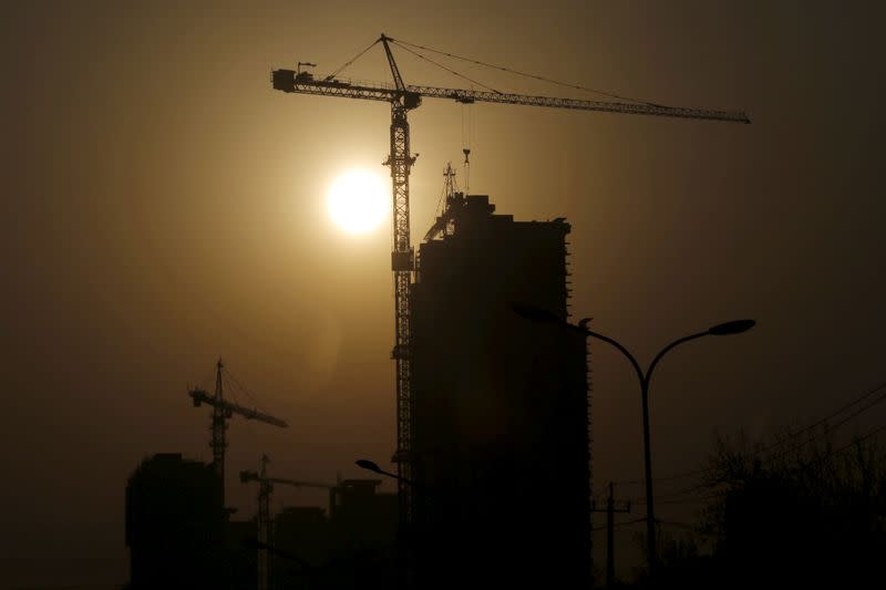 FILE PHOTO: A crane at a construction site is silhouetted against the rising sun in Beijing