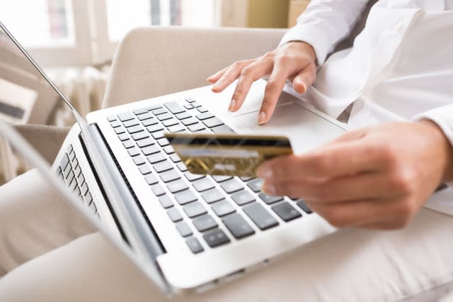 Woman's hands holding a credit card and using laptop for online shopping