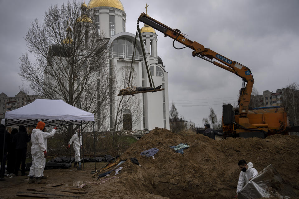 FILE - A crane lifts the corpse of a man from a mass grave to be identified in a morgue, in Bucha, on the outskirts of Kyiv, Ukraine, Sunday, April 10, 2022. Ministers from dozens of nations are meeting on Thursday, July 14, 2022 in the Netherlands to discuss with the International Criminal Court’s chief prosecutor how best to coordinate efforts to bring to justice perpetrators of war crimes in Ukraine. (AP Photo/Rodrigo Abd, File)