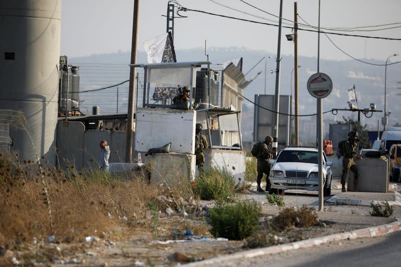 Israeli troops check cars at a checkpoint near a shooting scene in Huwara