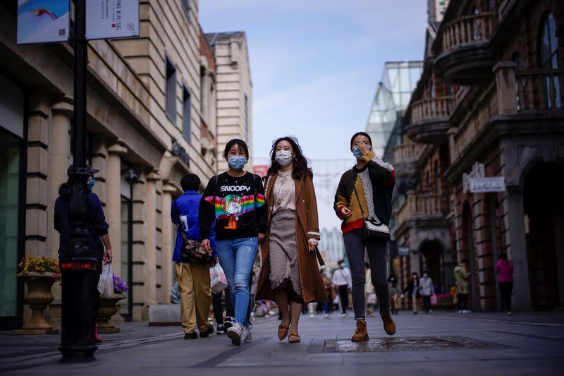 FILE PHOTO: People wearing face masks are seen at a main shopping area after the lockdown was lifted in Wuhan