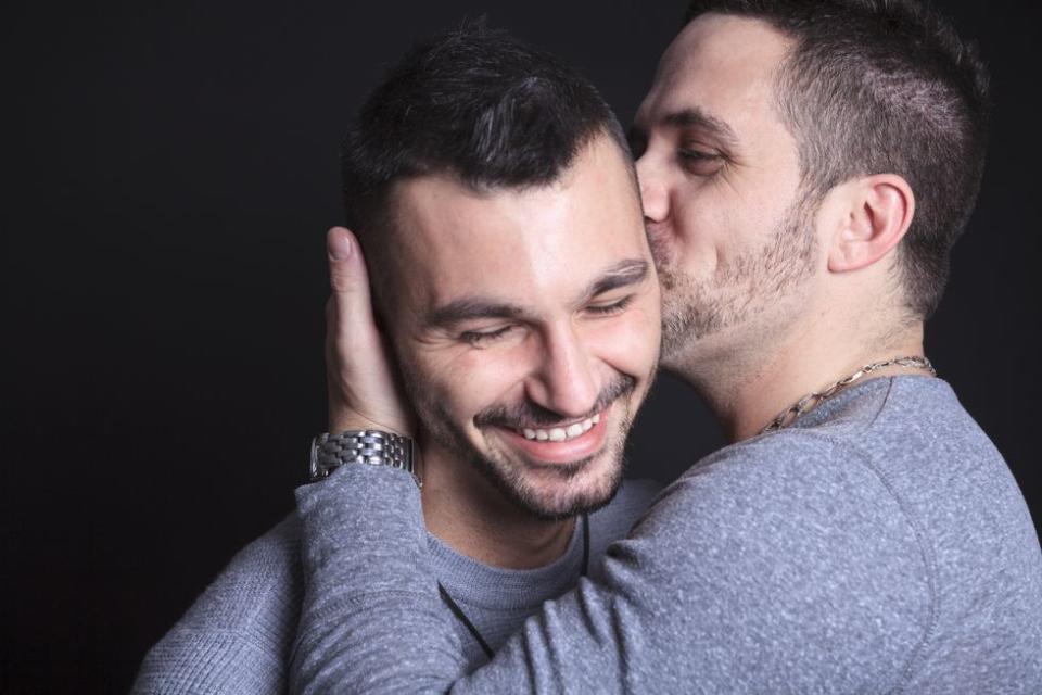 a man kissing another man's cheek