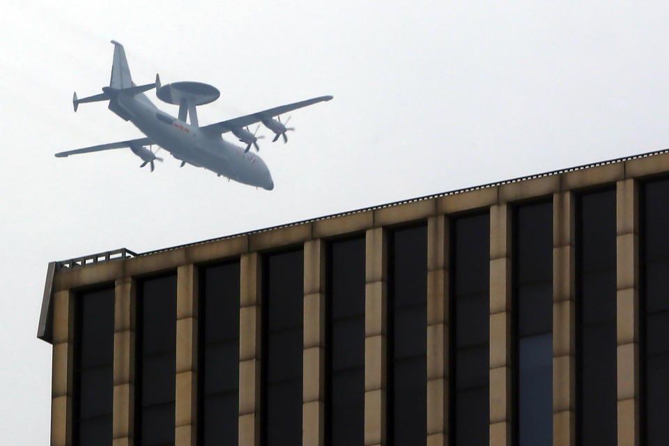 A Chinese military plane flies above the central business district in Beijing, Sunday, Sept. 15, 2019. Many of the streets in the central part of China's capital were shut down this weekend for a rehearsal for what is expected to be a large military parade on Oct. 1 to commemorate the 70th anniversary of Communist China. (AP Photo/Mark Schiefelbein)