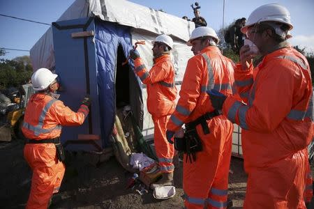 Workmen tear down makeshift shelters on the second day of the evacuation of migrants and their transfer to reception centers in France, as part of the dismantlement of the camp called the "Jungle" in Calais, France, October 25, 2016. REUTERS/Neil Hall